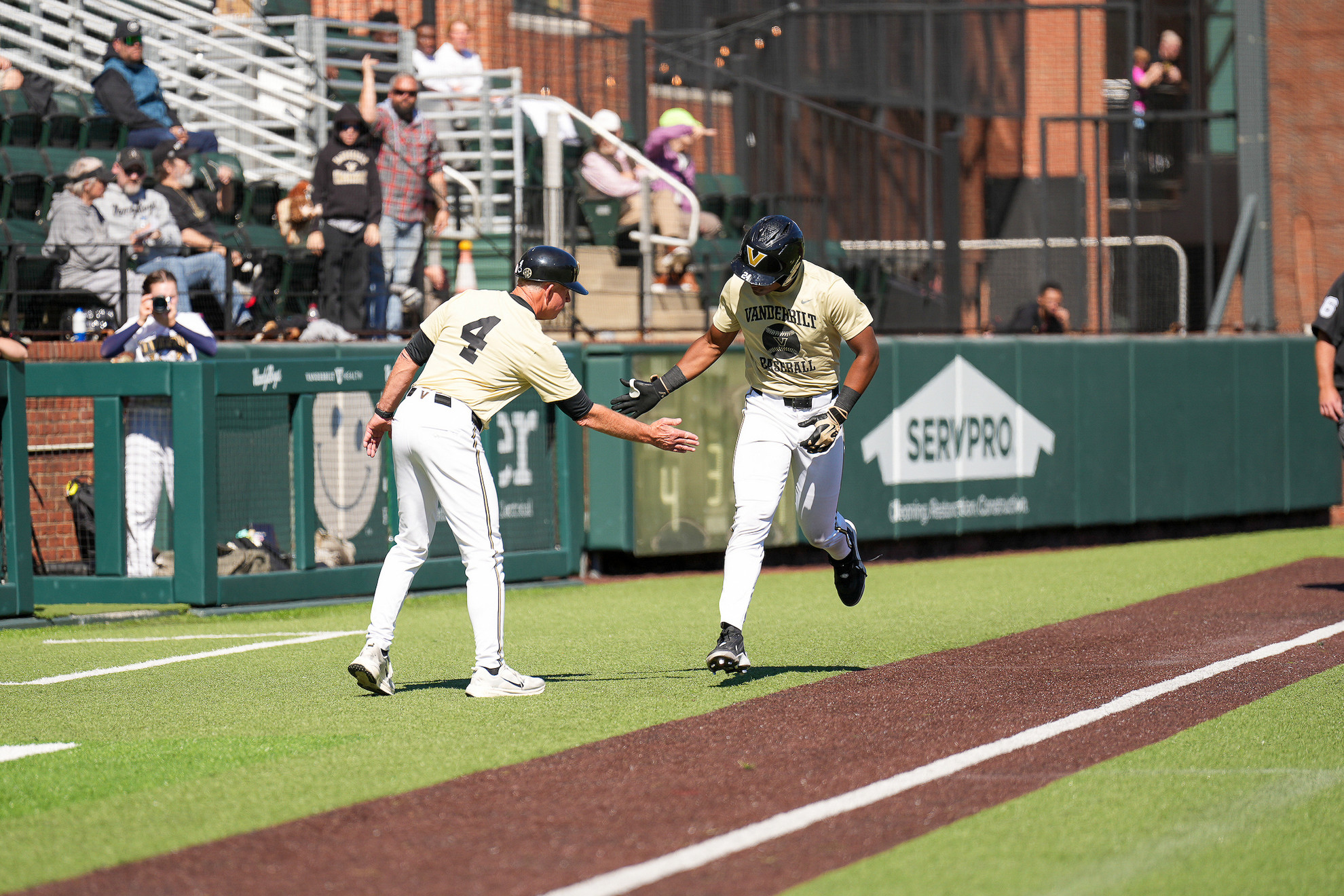 Two baseball players in Vanderbilt uniforms high-five on the field during a game.